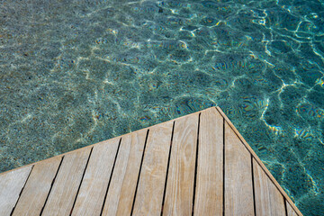 Top view of wood platform or terrace jetty beside the blue crystal clear water background