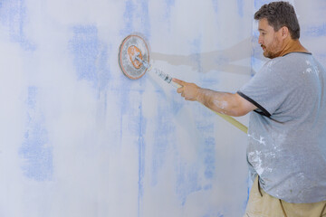 Man sanding the plaster plasterboard in drywall