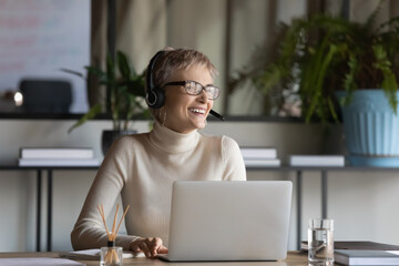 Overjoyed young caucasian businesswoman in headphones glasses have fun talking on video call on...