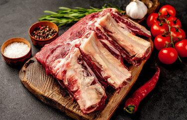 raw beef on the bone with spices on a stone background