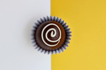 Gourmet chocolate truffle on white and yellow background. Cocoa ball, chocolate candy.