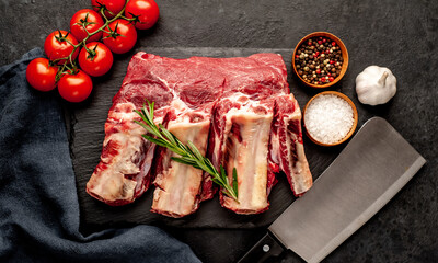 Fototapeta na wymiar raw beef on the bone with spices on a stone background