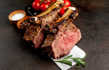 Baked beef on the bone with spices on a meat knife against a stone background