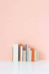 Books on a bookshelf and pink wall.