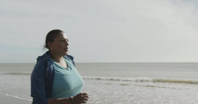 Overweight Mature black woman running cardio exercise on beach, African American female at sunrise exercising outdoors, body positive plus size model