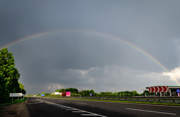 cloudy sky with rainbow, over motorway