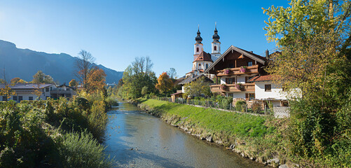 tourist destination Aschau im chiemgau, autumnal landscape with church and river Prien, upper...