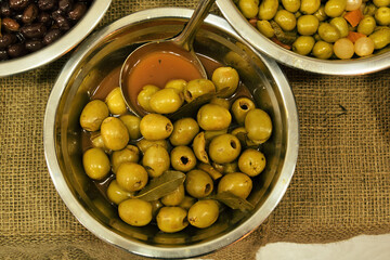 Bowls of different olives on a wooden table in a typical shop in Barcelona