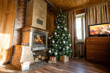 Photo of interior of room with a wooden wall, Christmas tree, fireplace. Christmas atmosphere. Home comfort