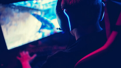 Professional gamer playing online games tournaments pc computer with headphones, Blurred red and...