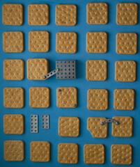 Crackers and constructor details on a blue background. Nuts and screws. Synesthesia. Iron cookie. An edible puzzle. High quality photo. Conceptual still life. Product photography. Different objects