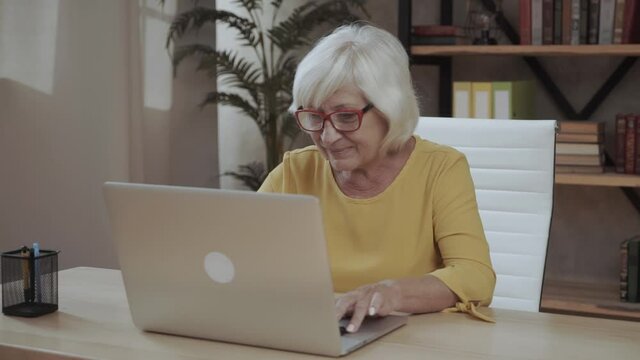 A senior concentrated business lady staring at the screen and lowered her eyeglasses while using laptop
