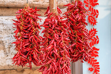Naklejka premium View close-up on garlands of dried red peppers hung on the counter of street spice shop in downtown Budapest, Hungary