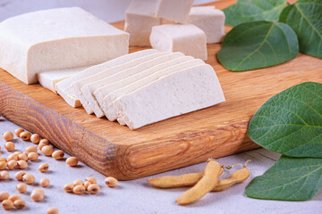 Tofu, also known as bean curd, diced on a wooden cutting board, closeup with selective focus