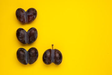 Intergrown double prunes. Ugly fruits on a yellow background with copy space. Vegetable or food...