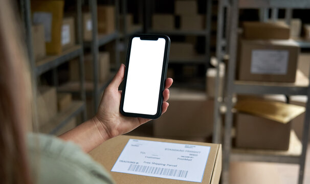 Female Warehouse Worker Seller, Small Stock Business Owner Holding Phone Mock Up Screen Ad Scan Retail Package Parcel Bar Code On Commercial Shipping Box Delivery Order On Smartphone Using Mobile App.