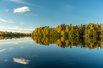 Beautiful autumn view across the Dal River in Sweden, with vibrant autumn colored trees mirroring in the dead calm water