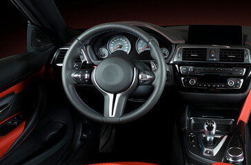 Obraz na płótnie Canvas Modern luxury car Interior - steering wheel, shift lever and dashboard. Car interior luxury.Steering wheel, dashboard, speedometer, display. Red and black perforated leather cockpit