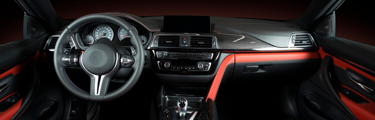 Plakat Modern luxury car Interior - steering wheel, shift lever and dashboard. Car interior luxury.Steering wheel, dashboard, speedometer, display. Red and black perforated leather cockpit