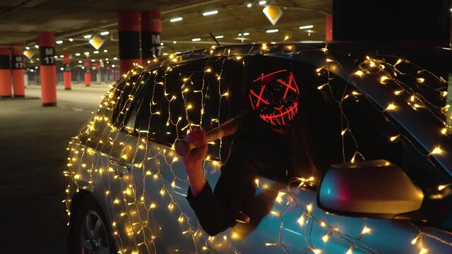The killer in the luminous mask holds a baseball bat in his hand. The new founding fathers are ready for judgment night. The car was decorated with a garland for Halloween.