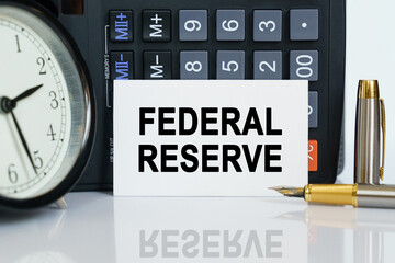 On the table there is a clock, a pen, a calculator and a business card on which the text is written - FEDERAL RESERVE