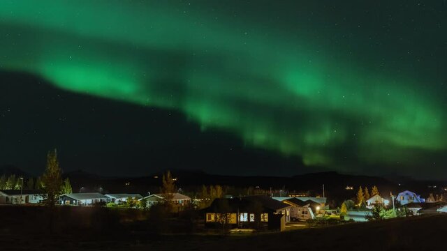 Time lapse of dancing aurora borealis on the night sky. Beautiful northern lights in Iceland above little village. A high quality 4K video