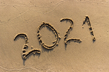 The year 2021 is written on the sandy shore. 2021 is approaching the beginning. Summer background. - 384883642