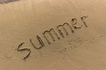 Summer written on the sandy shore. Summer ended and was washed away by a wave. Summer background. - 384883684