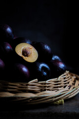 A stack of dark food-style black plums with copy space