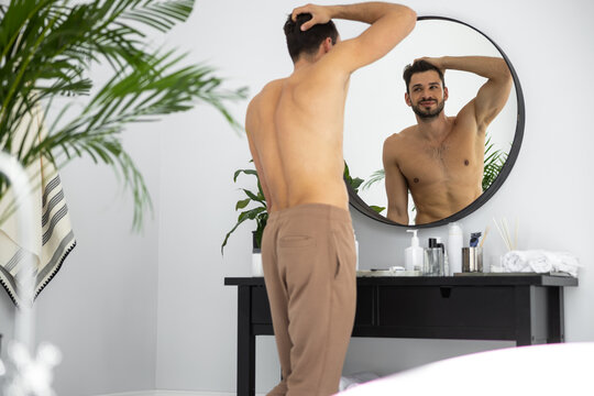 Waist up shot of man looking to himself through the mirror