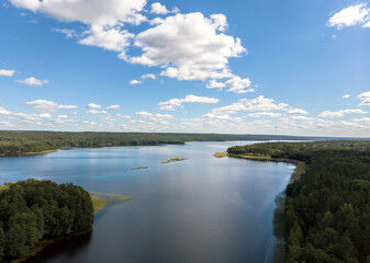 Fototapeta na wymiar Long forest lake, lots of clouds top view