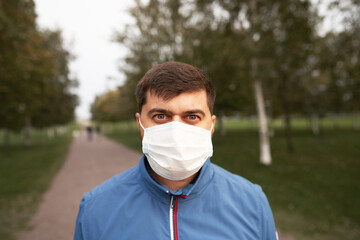 A man in a mask and gloves on the background of the Park, the beginning of autumn, the concept of...