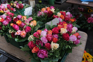 Moddy tone, Various vivid color of blooming roses in vase on table in front of stall at florist shop. Red orange pink and white blossom roses for Valentine day.