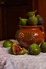 Dark food image of a jar with figs on a white decorated cloth
