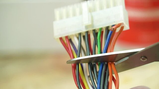 The wizard cut off the melted connector and burnt wires from a pair of scissors close up. Computer repair. workshop.