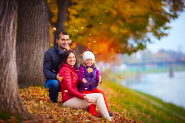Fototapeta premium happy family playing among fallen leaves in autumn park