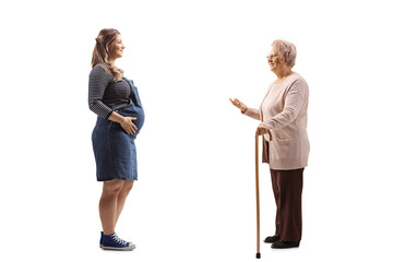 Full length profile shot of a pregnant woman and an elderly lady having a conversation