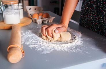 Unrecognized woman kneading the dough for bread with flour around on kitchen table. Homemade food concept. Food preparation. Cooking bread.