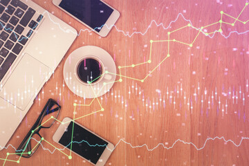 Double exposure of forex chart hologram over desktop with phone. Top view. Mobile trade platform...