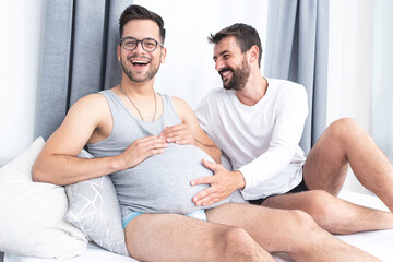 Happy gay man touching pregnant tummy of boyfriend