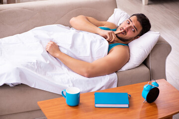 Young man lying on the sofa in time management concept