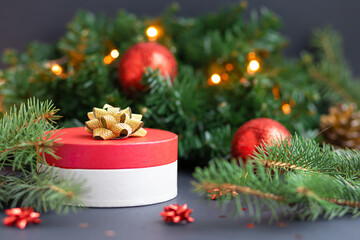 round red gift box with gold ribbon, bow and balls for the happy new year. surprise, present on the background of Christmas decoration. copy space, text, soft focus