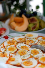 Boiled eggs with yoghurt sauce, tomato salda and various fruit on the breakfast table. Selective focus.