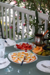 Boiled eggs with yoghurt sauce, tomato salda and various fruit on the breakfast table. Selective focus.