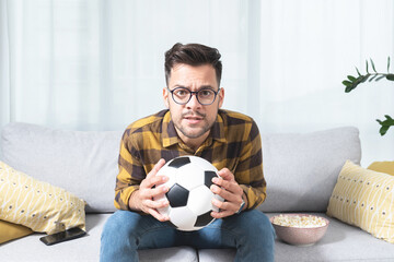 Nervous man watching football match at home