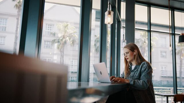 Young woman looking busy working on laptop at a cafe. Caucasian woman sitting in coffee shop using laptop.
