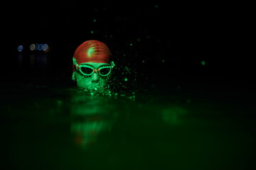 authentic triathlete swimmer having a break during hard training on night neon gel light