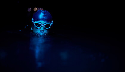 authentic triathlete swimmer having a break during hard training on night neon gel light