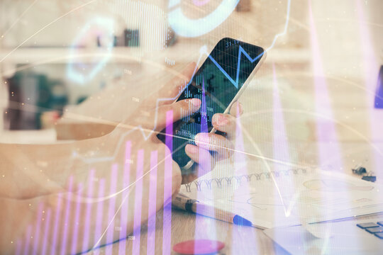 Double exposure of man's hands holding and using a digital device and forex graph drawing. Financial market concept.
