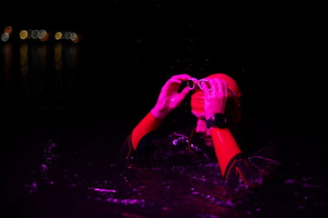 authentic triathlete swimmer having a break during hard training on night neon gel light